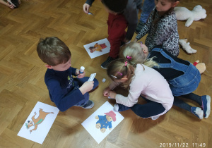 dzieci siedzą na podłodze dopasowują nazwę misia z jego zdjęciem